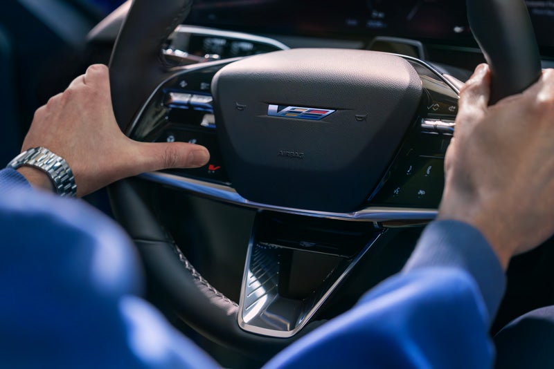 Close-up of a Man About to Press the V-Button on the 2026 OPTIQ-V Steering Wheel | Bergstrom Cadillac of Appleton in Appleton WI