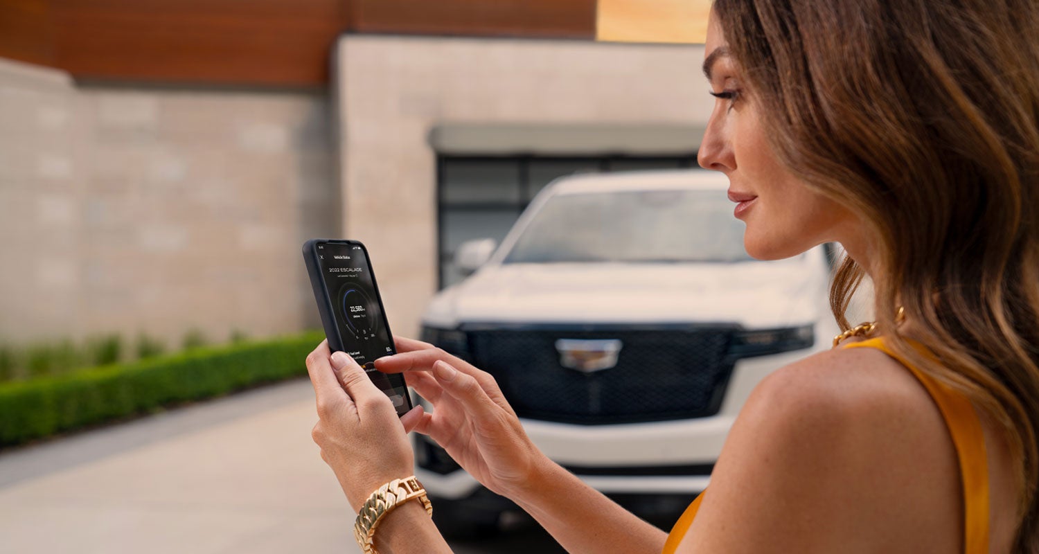 lady checking her mobile with a Cadillac vehicle background | Bergstrom Cadillac of Appleton in Appleton WI