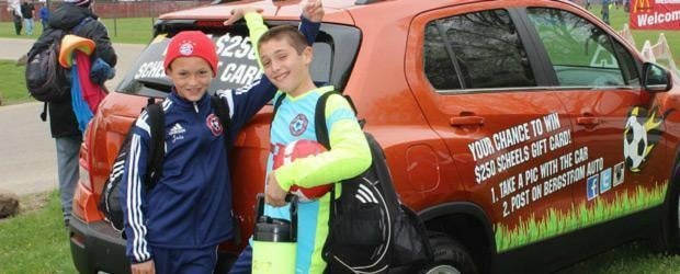 two kids posing in front of a car
